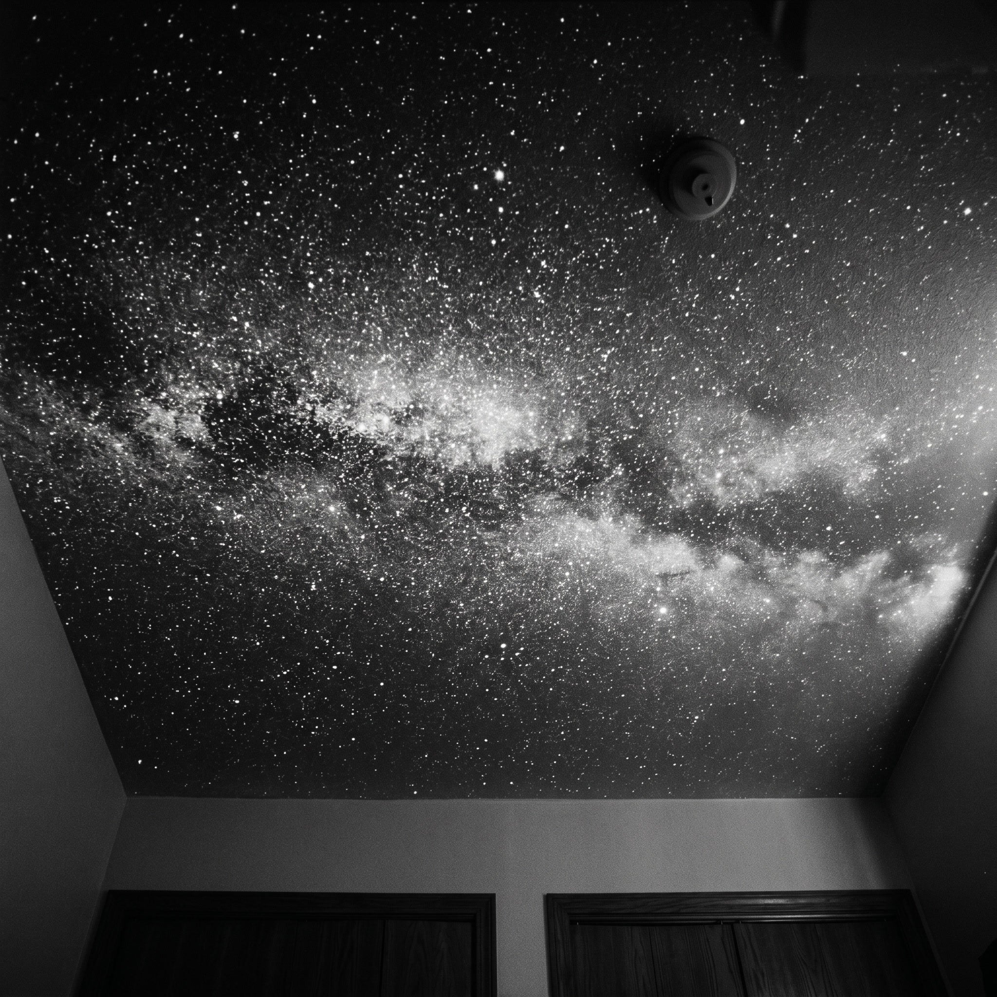 Bedroom ceiling covered in a black-and-white Milky Way projection